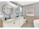 Modern bathroom features a double vanity with marble countertop and round mirrors at 11575 Wilson Cir, Parker, CO 80134
