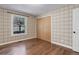 Cozy bedroom features wood floors, plaid wallpaper, window, and built-in closet at 7420 Windwood Way, Parker, CO 80134