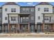 Modern townhomes with gray and white siding, brick accents, and black metal railings at 6824 Huddersfield Ln, Castle Pines, CO 80108