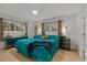 Bright main bedroom with teal bedding and wood floors at 5965 W Quarles Dr, Littleton, CO 80128