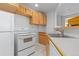 Basement kitchenette features white appliances, tile flooring, wood cabinets, and plenty of counter space at 2509 S Bahama Way, Aurora, CO 80013