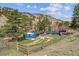 Aerial view of a blue ranch home and detached structure surrounded by a rustic wooden fence and trees at 5384 Olde Stage Rd, Boulder, CO 80302