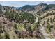 Scenic aerial view of a mountain community with a blue ranch home, surrounded by lush trees and mountain views at 5384 Olde Stage Rd, Boulder, CO 80302