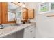 Bright bathroom with a granite countertop, oak cabinetry, and a decorative window with a colorful flower design at 5384 Olde Stage Rd, Boulder, CO 80302