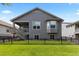 View of the home's backyard, showing a covered deck, bay window, and manicured lawn with black metal fencing at 15802 Xanthia Way, Thornton, CO 80602