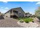 Side view of the home and back yard showing the covered deck, gravel, and black metal fencing at 15802 Xanthia Way, Thornton, CO 80602