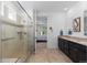 Well-lit bathroom with a glass-enclosed shower, double vanity and tile floor at 15802 Xanthia Way, Thornton, CO 80602