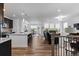 Open-concept living room featuring hardwood floors, white walls, and a modern kitchen island at 15802 Xanthia Way, Thornton, CO 80602