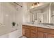 Bright bathroom featuring double sinks, wooden cabinets, and a tub with a shower at 18948 E Baker Pl, Aurora, CO 80013