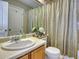 Cozy bathroom with wood vanity, white sink, toilet, and shower with striped curtain at 6462 Freeport Dr, Highlands Ranch, CO 80130