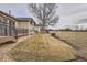 Backyard view from grass level looking up at house with stone accents, deck and expansive field at 16399 Somerset Dr, Broomfield, CO 80023
