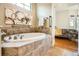 A bathroom featuring a large soaking tub, tile surround, mounted artwork, and bathroom access at 16399 Somerset Dr, Broomfield, CO 80023