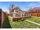 Charming backyard featuring a wooden deck with black metal railings, lush green grass, and wooden fence at 2772 Julian St, Denver, CO 80211