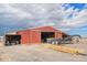A red barn with an open entrance and a trailer parked beside a large pile of lumber at 1222 S County Road 185, Byers, CO 80103