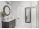 Updated bathroom with round mirror over a vanity and a view of the tiled shower at 1222 S County Road 185, Byers, CO 80103