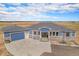 A charming blue ranch style home with stone accents, gray shingles, and a spacious driveway at 1222 S County Road 185, Byers, CO 80103