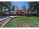 This charming single story house features a vibrant red door and attached garage in a verdant setting at 12378 E Cedar Cir, Aurora, CO 80012