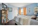 Inviting bedroom with a bright blue wall, light striped bedding, hardwood floors, and charming decorations at 12705 Home Farm Dr, Westminster, CO 80234