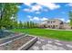 Large backyard with a garden, stone walkway, green lawn, and covered patio on a sunny day at 6566 S Telluride St, Aurora, CO 80016