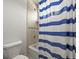Bathroom featuring a toilet, shower/bath, and neutral tile with a blue and white striped shower curtain at 6566 S Telluride St, Aurora, CO 80016