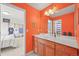 Bathroom features wooden vanity, orange paint, and mirrored wall to enhance spaciousness and style at 6566 S Telluride St, Aurora, CO 80016