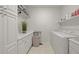 Well-lit laundry room with white cabinets, shelving, folding counter, and a front-loading washer and dryer at 6566 S Telluride St, Aurora, CO 80016