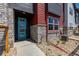 A lovely townhome entryway with a teal door, stone details, and landscaping at 2877 E 103Rd Dr, Thornton, CO 80229