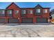 Three-unit townhome showing garages and red and dark grey color scheme at 2877 E 103Rd Dr, Thornton, CO 80229