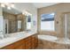 Bright bathroom featuring dual sinks, a soaking tub, and a glass door shower stall with natural lighting at 15046 Verbena St, Thornton, CO 80602