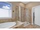 Lovely soaking tub and glass shower stall with tiled walls and natural light from a window at 15046 Verbena St, Thornton, CO 80602