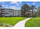 Spacious condo building with well-maintained lawn and mature trees, set against a blue sky at 725 S Alton Way # 7D, Denver, CO 80247