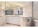 Bathroom featuring white cabinets, a large mirror, and gray tiling throughout at 1300 S Monaco Pkwy # 12, Denver, CO 80224