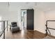 Open loft space with a lounge chair and a modern sliding barn door at 1300 S Monaco Pkwy # 12, Denver, CO 80224