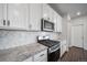 Stylish kitchen with white cabinets, granite countertops, and stainless steel appliances, perfect for modern cooking at 18189 House Finch Ln, Parker, CO 80134