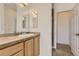 Bright bathroom features a sink with a large mirror, a wooden vanity, and a door to the shower at 3491 Cascina Pl # D, Highlands Ranch, CO 80126