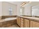 Bright bathroom features a soaking tub with tile surround, double sink vanity, and large mirror at 3491 Cascina Pl # D, Highlands Ranch, CO 80126