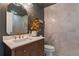 Charming bathroom featuring a wood vanity, white countertop, decorative mirror, and chic wall texture at 13563 E 106Th Pl, Commerce City, CO 80022