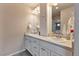 Bathroom featuring dual sinks, white cabinets, a large mirror, and modern fixtures at 13563 E 106Th Pl, Commerce City, CO 80022