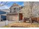 Charming two-story home with a stone and siding facade, manicured lawn, and a blooming tree in the front yard at 13563 E 106Th Pl, Commerce City, CO 80022