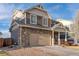View of the home's facade displaying the stone accents, siding, attached two-car garage, and a driveway at 13563 E 106Th Pl, Commerce City, CO 80022