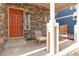 Inviting front porch featuring a brick accent wall, seating area, and a vibrant orange front door at 13563 E 106Th Pl, Commerce City, CO 80022