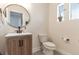 Cozy powder room with a wood vanity, modern faucet, round mirror, and stylish fixtures at 13563 E 106Th Pl, Commerce City, CO 80022