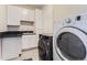 Well-equipped laundry room features modern appliances, white cabinets, and a black countertop at 9724 Cantabria Pt, Lone Tree, CO 80124