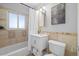 A full bathroom featuring decorative stone-look wall accents, a sink, toilet, tub, and shower at 3137 S Glencoe St, Denver, CO 80222