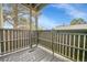 View of the private balcony with wood floors and rail, overlooking the yard and trees on a sunny day at 9700 E Iliff Ave # D44, Denver, CO 80231