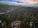 Scenic aerial view of a home nestled among lush evergreen trees with mountains in the background at 28254 Tresine Dr, Evergreen, CO 80439