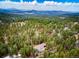 Breathtaking aerial view of a secluded home surrounded by lush forest and distant mountain ranges at 28254 Tresine Dr, Evergreen, CO 80439