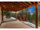 Covered back porch with string lights and hanging chair, great for relaxing and enjoying the view at 28254 Tresine Dr, Evergreen, CO 80439