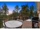 Inviting outdoor deck furnished with a dining table, chairs, grill, and scenic views of wooded landscape at 28254 Tresine Dr, Evergreen, CO 80439