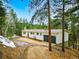 Charming single-story home with a two-car garage nestled among mature pine trees on a sunny day at 28254 Tresine Dr, Evergreen, CO 80439
